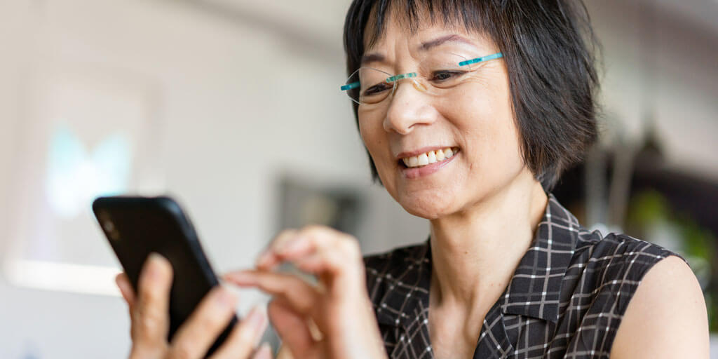 Middle-aged woman wearing eye glasses, interacting on her mobile phone.