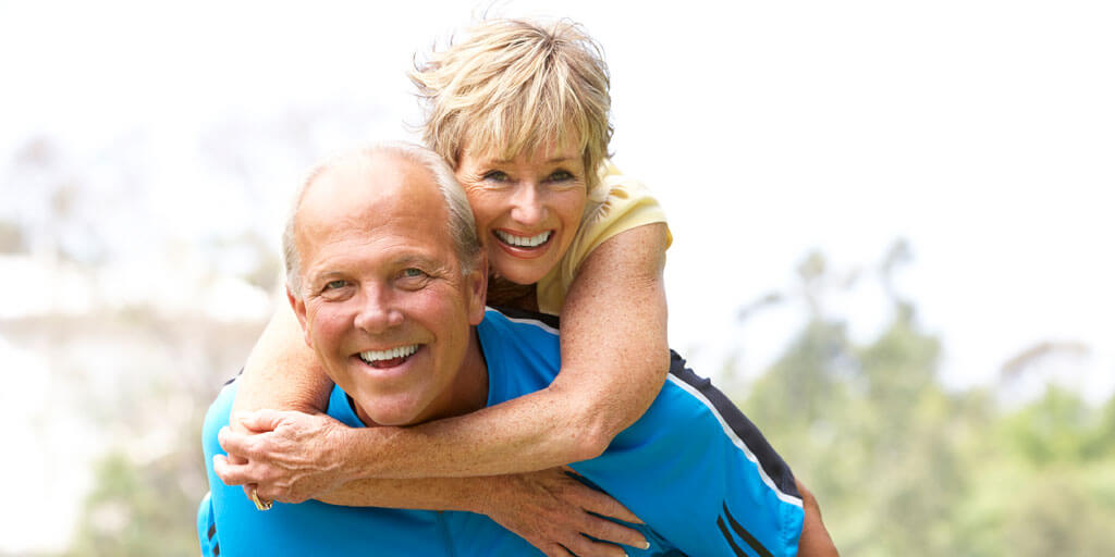 Senior couple hugging outside looking at camera