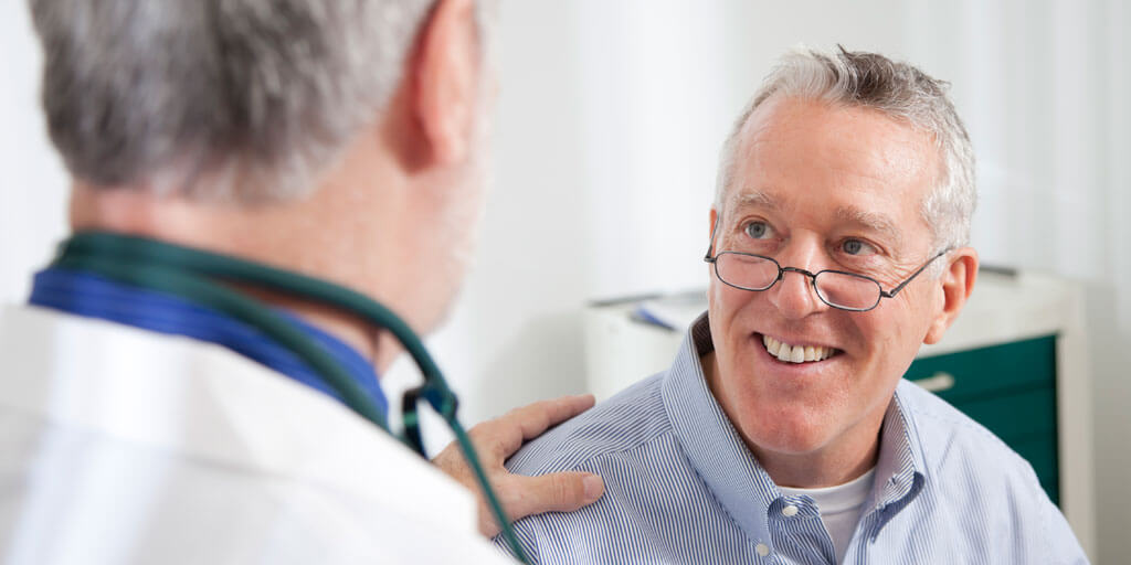 Senior man with eye glasses talking with his doctor.