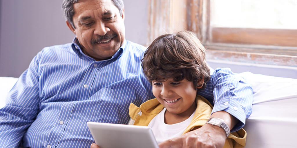 Man sitting with his son viewing and pointing at tablet