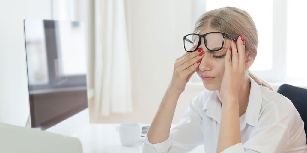 Young woman rubbing her eyes at her computer