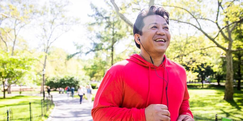 A middle-aged man is running outdoors without the need for eyeglasses or contacts.