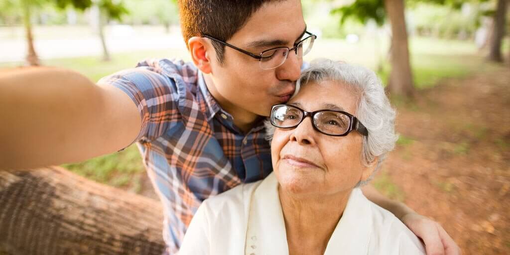 Young man hugging his disabled grandmother outside