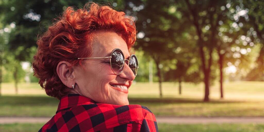 Une femme d'âge moyen dehors portant des lunettes de soleil pour protéger ses yeux du soleil.