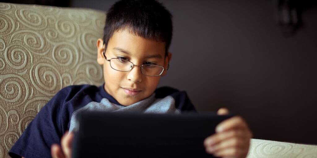 A young boy with eyeglasses using a digital tablet.