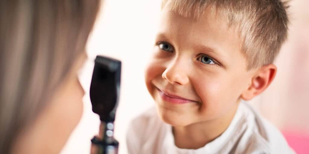 A young boy getting an eye exam from his eye doctor.