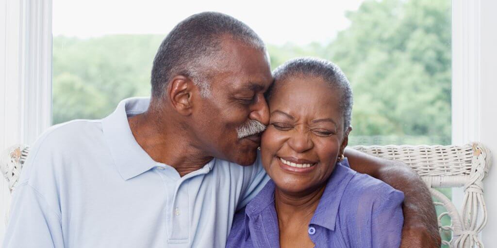 50+ African-American couple hugging and smiling.