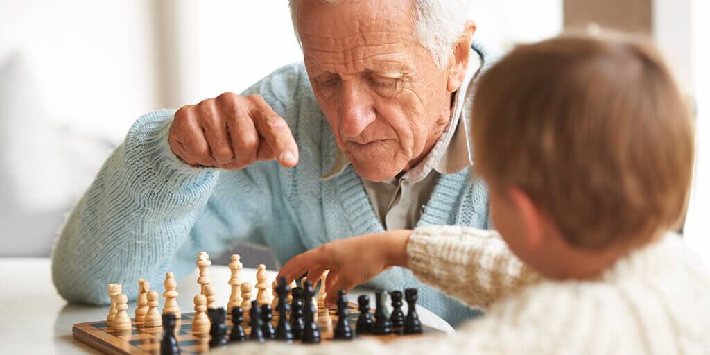Teaching his grandson about chess A grandfather teaching his grandson how to play chess
