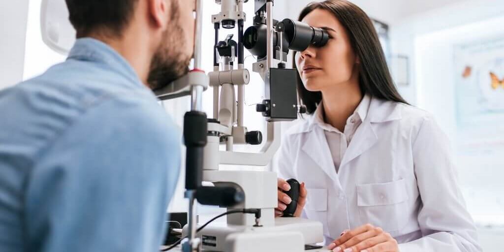 Doctor and patient in ophthalmology clinic Attractive female doctor ophthalmologist is checking the eye vision of handsome young man in modern clinic. Doctor and patient in ophthalmology clinic.