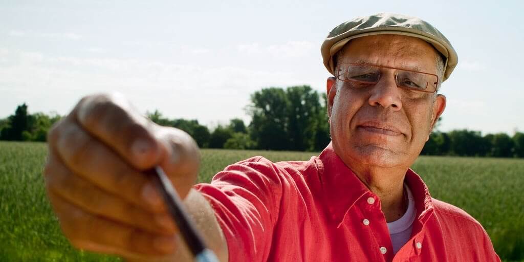 A senior man wearing eyeglasses on a golf course.